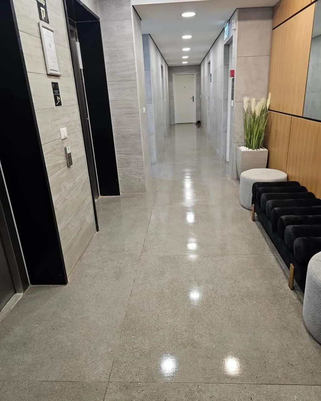 מסדרון לובי נקי ומואר המוביל למעליות בבניין בניהול אל ג׳י